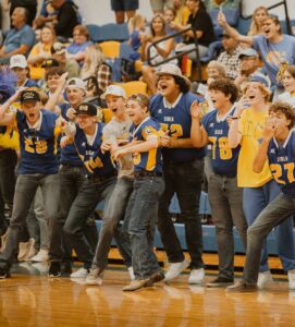 young men show their enthusiasm and school spirit from the sidelines in gym during homecoming week