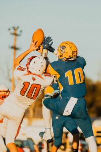 football players both leap for the ball during a pass interception