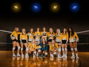 2023 high school volleyball girls team poses in gym for team picture