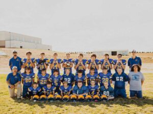 2023 junior high boys football team poses for team picture on field with school in background